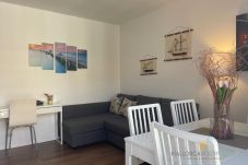 Living-dining room with a gray sofa, white table, chairs, and nautical decorations on the wall